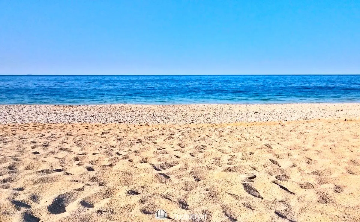 La sabbia dorata, i ciottoli bianchi e il mare blu della spiaggia di Mezzavalle