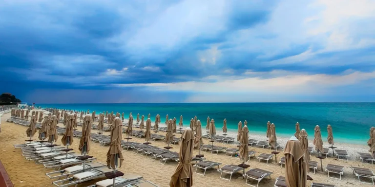 Gli ombrelloni bianchi sulla sabbia dorata e il mare blu della spiaggia di Portonovo