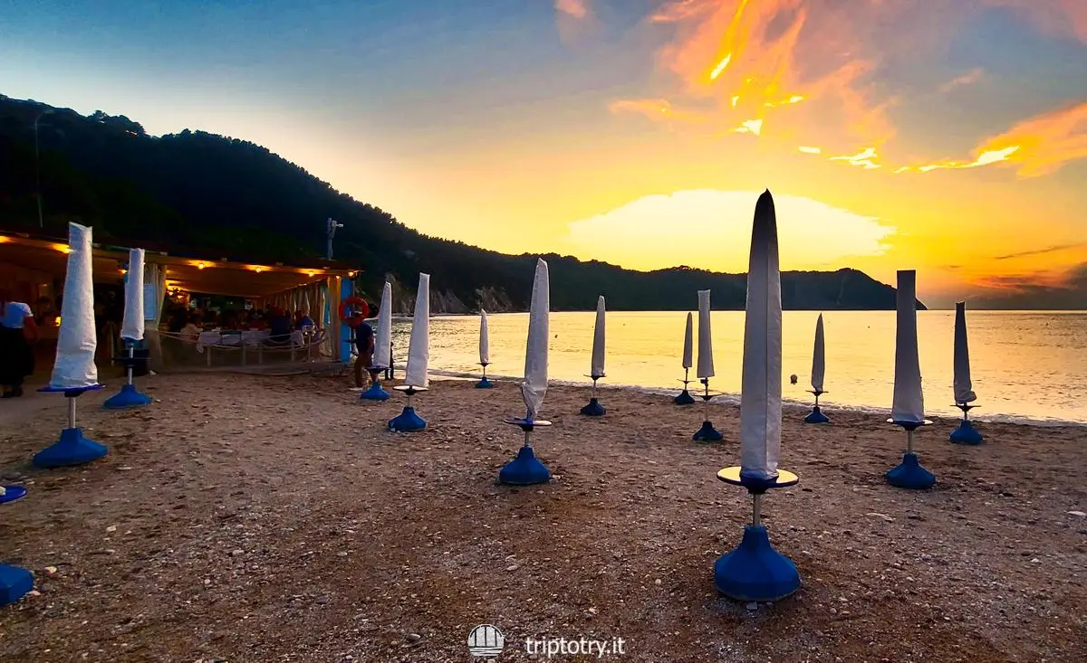Il tramonto scende sulla spiaggia di Portonovo e si accendono le luci nei ristoranti sulla spiaggia